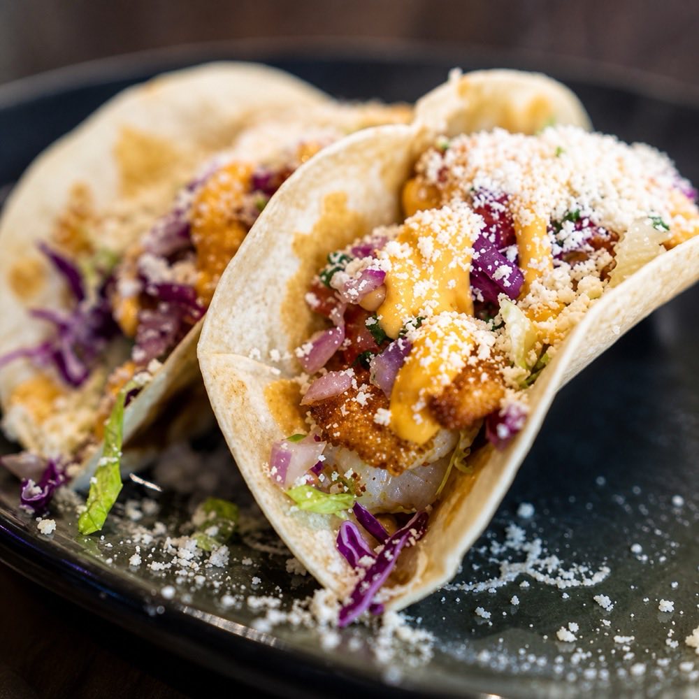 Tacos topped with cotija cheese, red cabbage and chipotle crema.